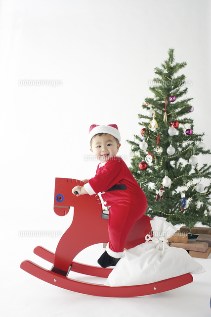 サンタクロースの衣装で赤い木馬に乗る赤ちゃん の写真素材 イラスト素材 アマナイメージズ