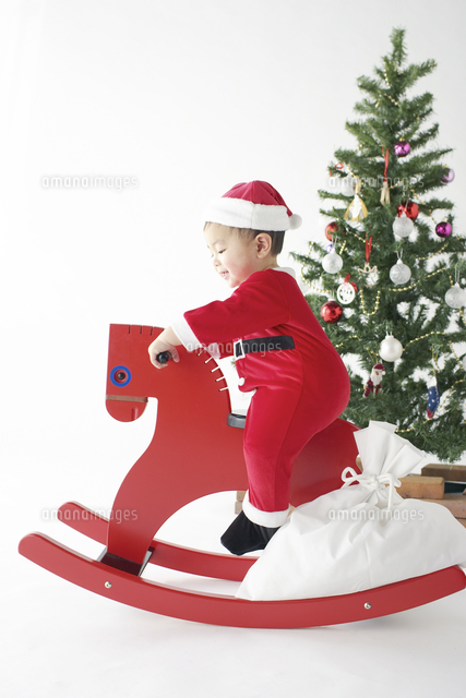 サンタクロースの衣装で赤い木馬に乗る赤ちゃん の写真素材 イラスト素材 アマナイメージズ