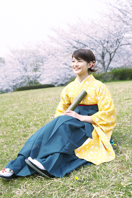 桜の前の芝生に座る袴姿の女子大学生 の写真素材 イラスト素材 アマナイメージズ