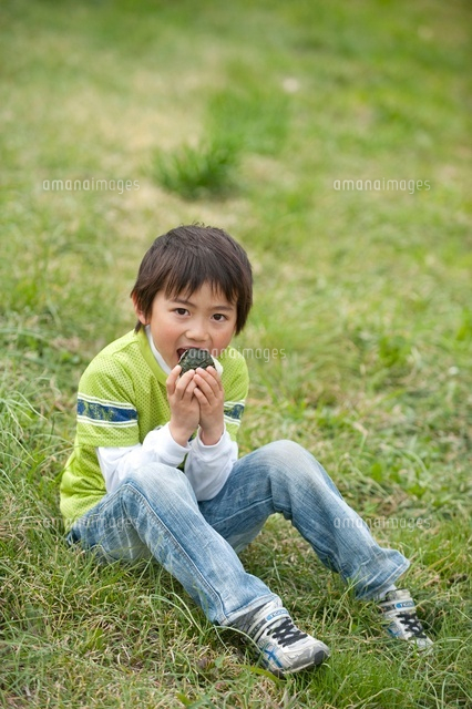 土手の草に座っておにぎりを食べる男の子 の写真素材 イラスト素材 アマナイメージズ