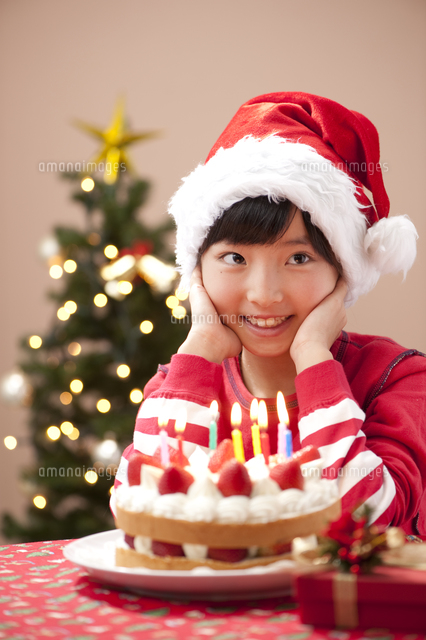 クリスマスでケーキとプレゼントを前に微笑む女の子[10248004226]の 