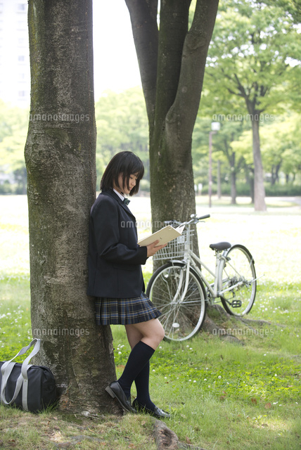 木陰で読書する女子高生と自転車 の写真素材 イラスト素材 アマナイメージズ