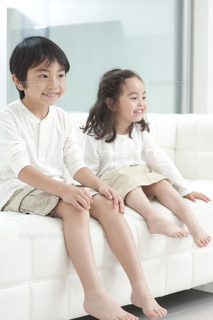 リビングのソファに座る子供男女 の写真素材 イラスト素材 アマナイメージズ