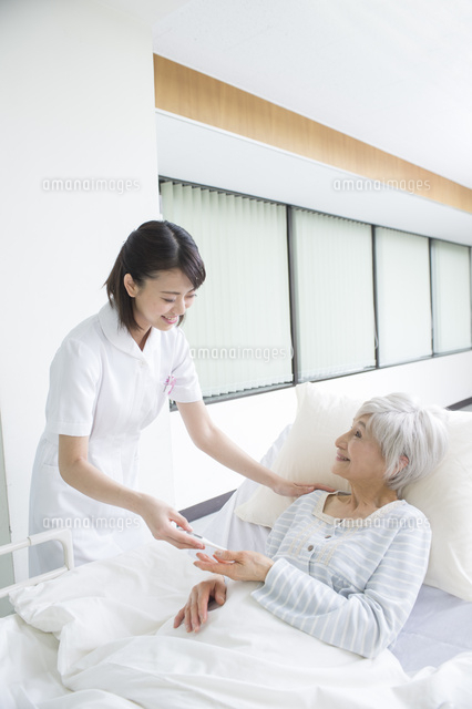 ベッドの入院シニア女性患者に体温計を渡す看護師 の写真素材 イラスト素材 アマナイメージズ