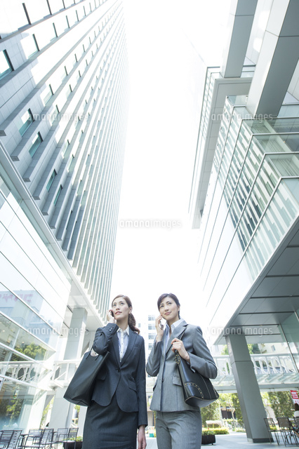 オフィスビルで電話するｏｌ２人 の写真素材 イラスト素材 アマナイメージズ