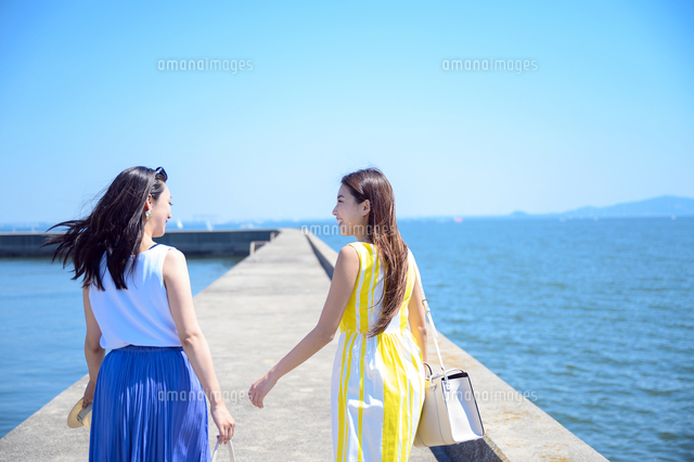 港の防波堤を歩く海のリゾートへ旅する女性2人 の写真素材 イラスト素材 アマナイメージズ