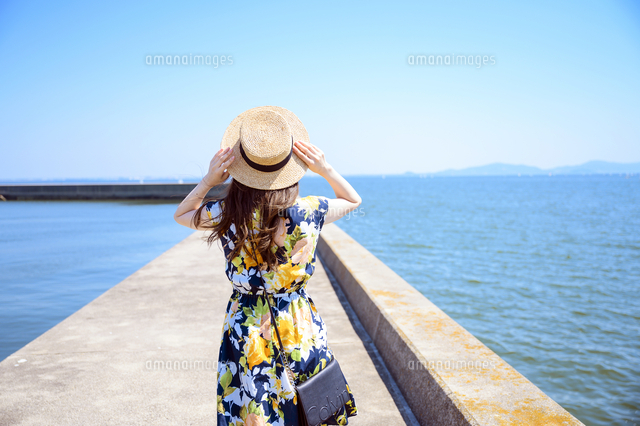 港の防波堤を歩く海のリゾートへ旅する女性 の写真素材 イラスト素材 アマナイメージズ