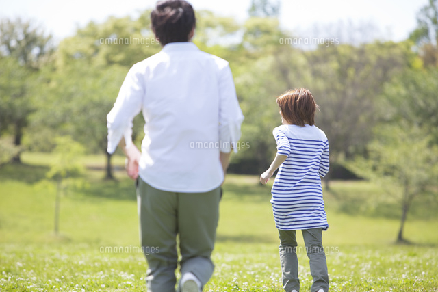 公園を走るカップルの後ろ姿 の写真素材 イラスト素材 アマナイメージズ