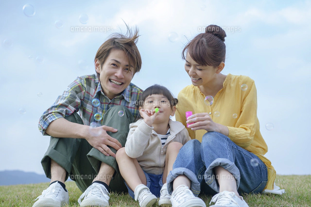 シャボン玉をする娘に寄りそう夫婦[10250006149]の写真・イラスト素材