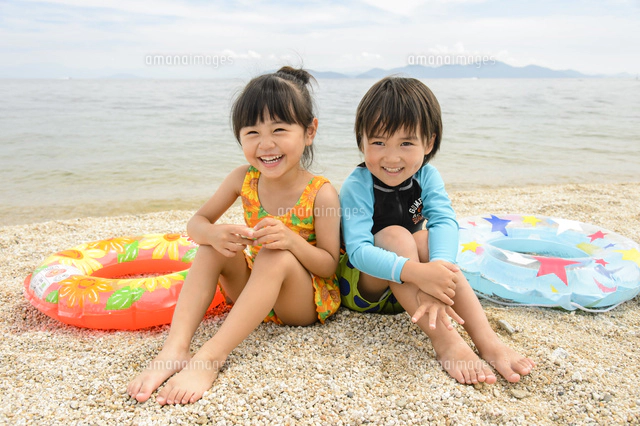 海辺の砂浜でうつ伏せになる水着の子供[10264007041]の写真・イラスト