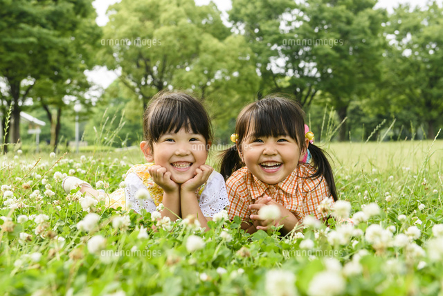 新緑のお花畑で並んで寝そべる女の子 の写真素材 イラスト素材 アマナイメージズ
