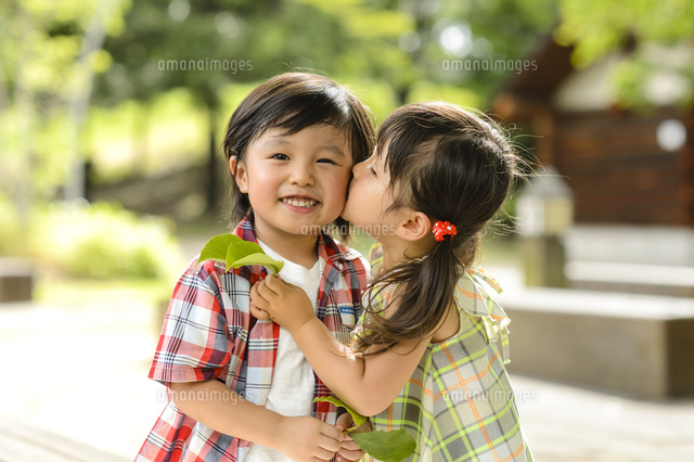 男の子の耳元にキスする女の子 の写真素材 イラスト素材 アマナイメージズ