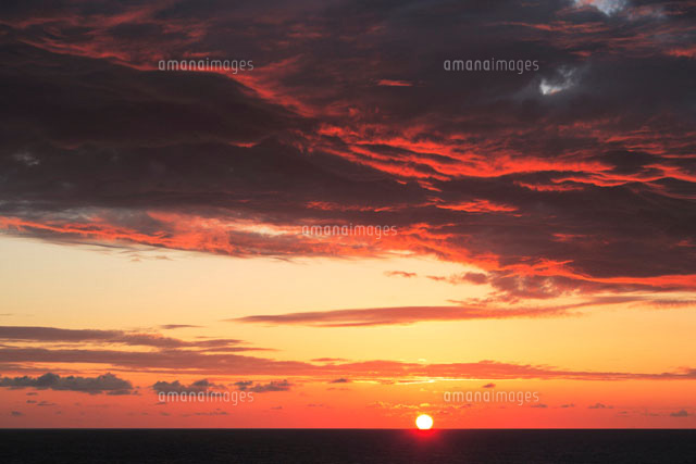 夕焼けに染まる空と雲と水平線に沈む太陽[10266000080]の写真