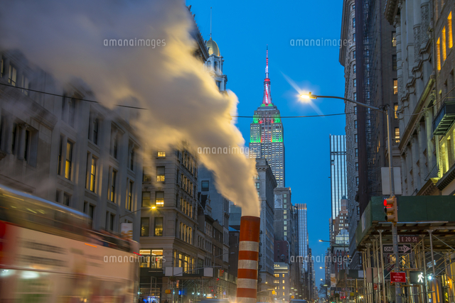 夕暮れの五番街で街頭の灯りに照らされ漂う蒸気の後ろでクリスマスカラーに輝くエンパイヤーステートビルデ の写真素材 イラスト 素材 アマナイメージズ