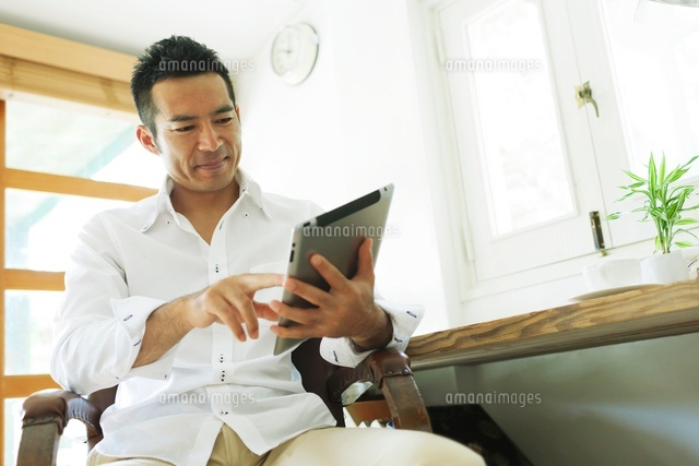 タブレットpcを操作する日本人の男性 の写真素材 イラスト素材 アマナイメージズ