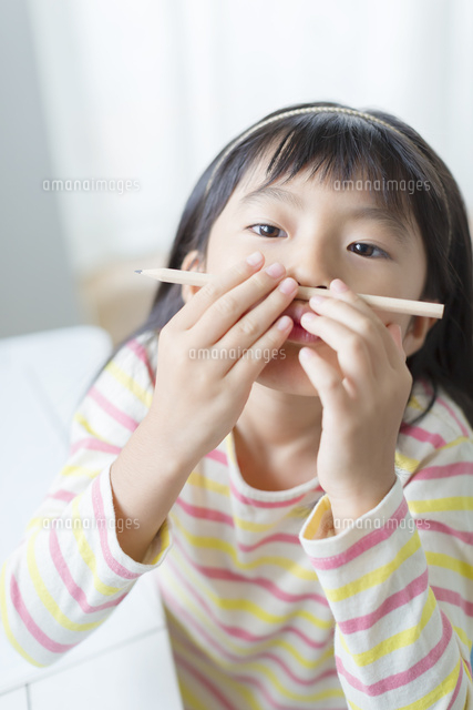 鉛筆を鼻にのせる小学生の女の子 の写真素材 イラスト素材 アマナイメージズ