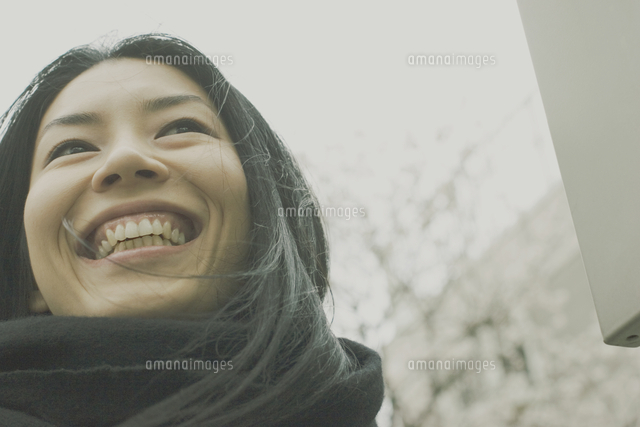 桜の木の前に立つ笑顔の日本人女性 の写真素材 イラスト素材 アマナイメージズ