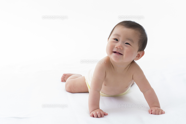白いシーツの上で腹ばいになっている笑顔の赤ちゃん の写真素材 イラスト素材 アマナイメージズ