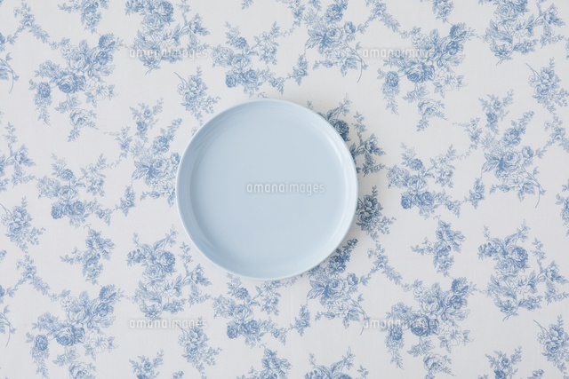 水色の花柄のコットンの布と水色の皿 の写真素材 イラスト素材 アマナイメージズ