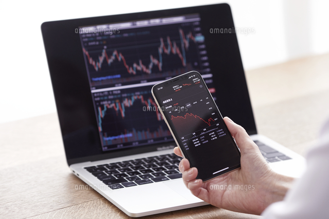 パソコンとスマートフォンでお金の管理をする女性 の写真素材 イラスト素材 アマナイメージズ