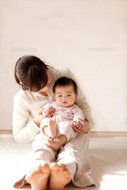 赤ちゃんをひざに乗せてあやすお母さん[10337000314]の写真・イラスト
