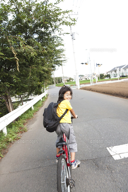 道路を自転車に乗って走る男の子の後ろ姿 の写真素材 イラスト素材 アマナイメージズ