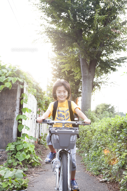 道路を自転車に乗って走る笑顔の男の子 の写真素材 イラスト素材 アマナイメージズ