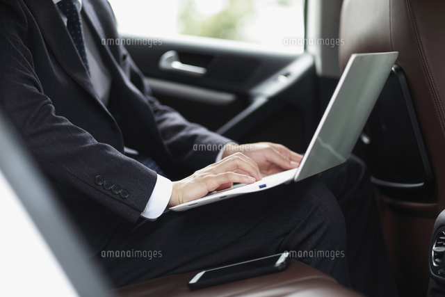 車の中でノートパソコンを操作しているビジネスマン の写真素材 イラスト素材 アマナイメージズ