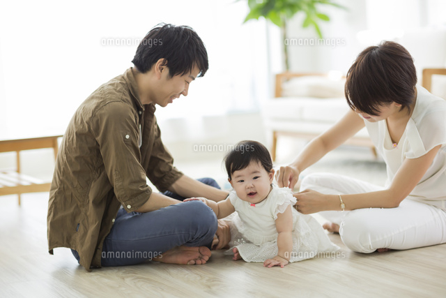 赤ちゃんに服を着せる両親 の写真素材 イラスト素材 アマナイメージズ