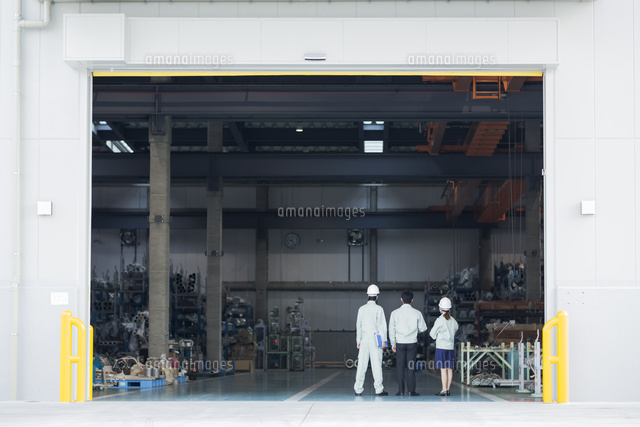 工場で立つ男女作業員の後姿 の写真素材 イラスト素材 アマナイメージズ