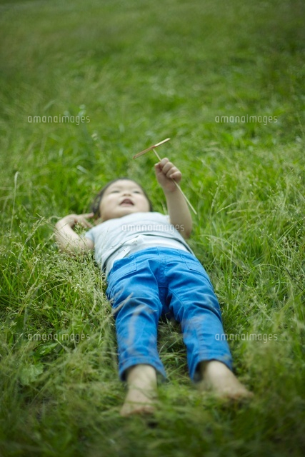 竹とんぼを持って草むらに寝転ぶ子供 の写真素材 イラスト素材 アマナイメージズ