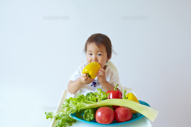 野菜の前に座りパプリカをかじる幼児 の写真素材 イラスト素材 アマナイメージズ