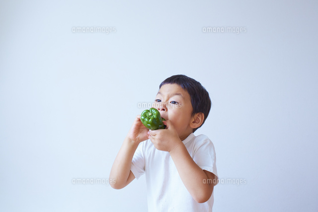 ピーマンをかぶりついて食べる子供 の写真素材 イラスト素材 アマナイメージズ