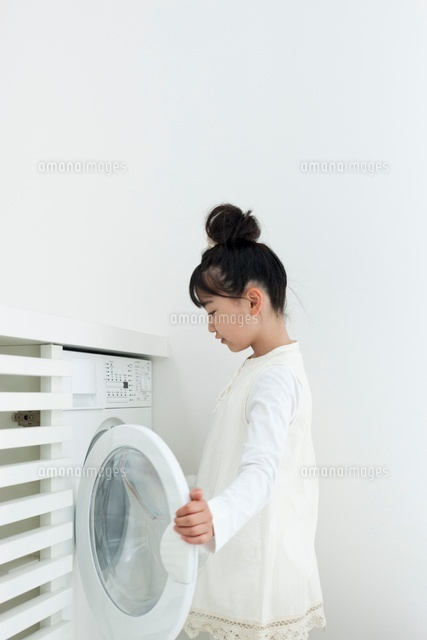 洗濯機に洗濯物を入れる女の子 の写真素材 イラスト素材 アマナイメージズ