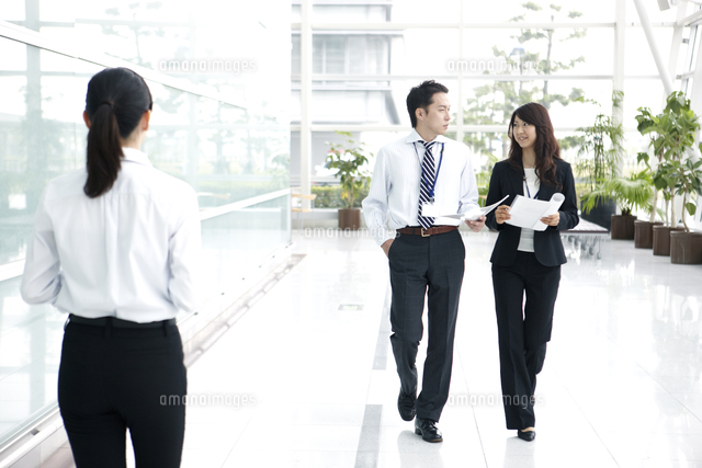 書類を手に話しながら歩く男女のビジネスマン の写真素材 イラスト素材 アマナイメージズ