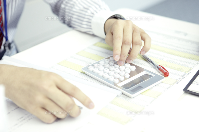 電卓を打つビジネスマンの手元 の写真素材 イラスト素材 アマナイメージズ