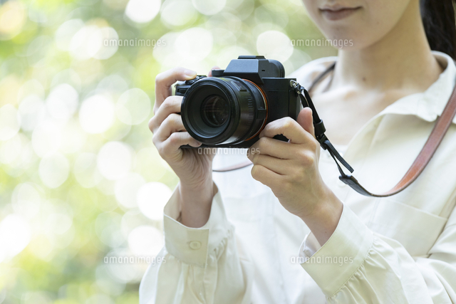 自然の中でカメラを構える若い女性 の写真素材 イラスト素材 アマナイメージズ