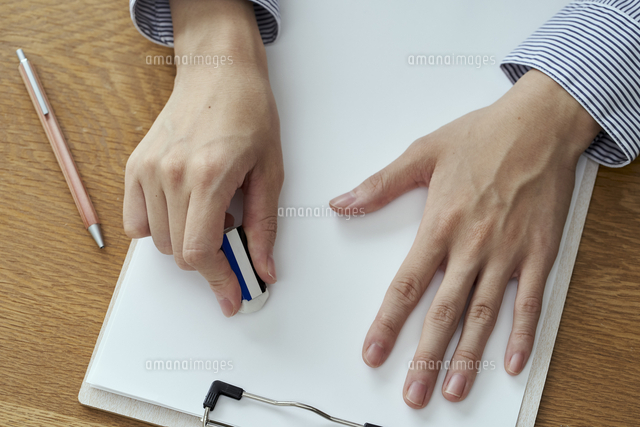 消しゴムで書類の文字を消す女性の手元 の写真素材 イラスト素材 アマナイメージズ