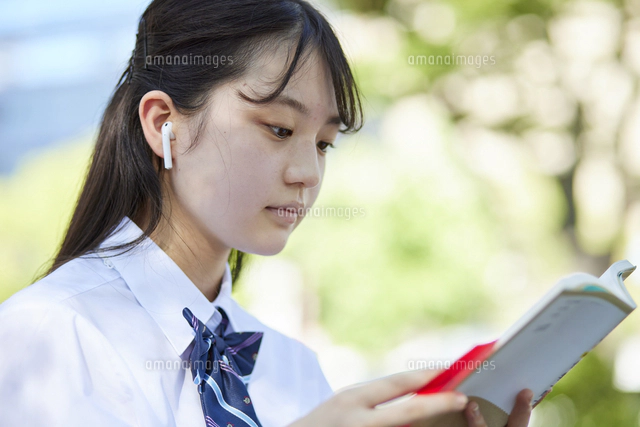 ワイヤレスイヤホンで音楽を聴く女子高生[10521007678]の写真