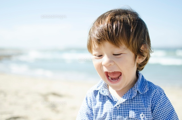 海をバックに大きな口を開けて笑うハーフの男の子 の写真素材 イラスト素材 アマナイメージズ