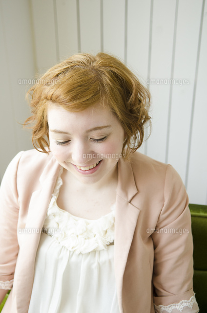 部屋の中で下を向いて笑うハーフの女性 の写真素材 イラスト素材 アマナイメージズ