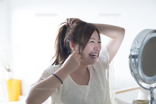 鏡を見ながら髪を結ぶ女性 の写真素材 イラスト素材 アマナイメージズ