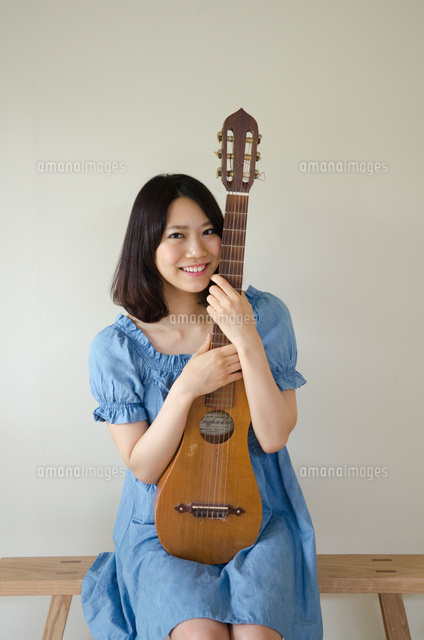ギターを抱えている笑顔の女性 の写真素材 イラスト素材 アマナイメージズ