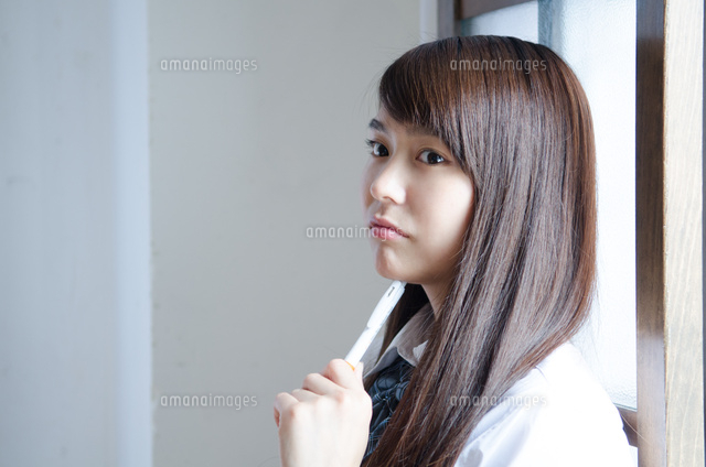 ペンを持って考えている制服姿の女性 の写真素材 イラスト素材 アマナイメージズ