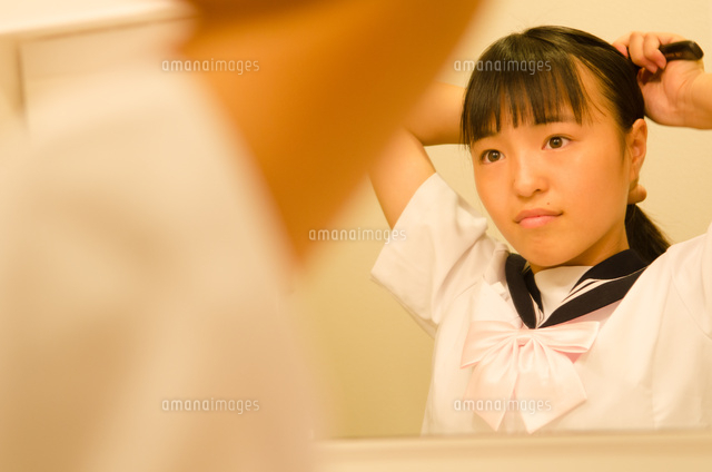 髪を結いながら鏡を見る女の子 の写真素材 イラスト素材 アマナイメージズ