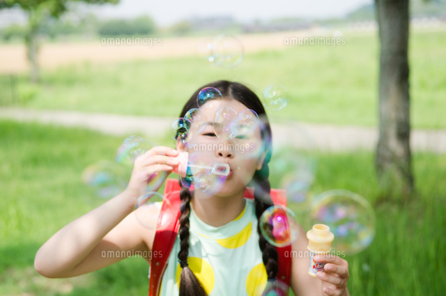 ランドセルを背負ってシャボン玉を吹いている女の子 の写真素材 イラスト素材 アマナイメージズ