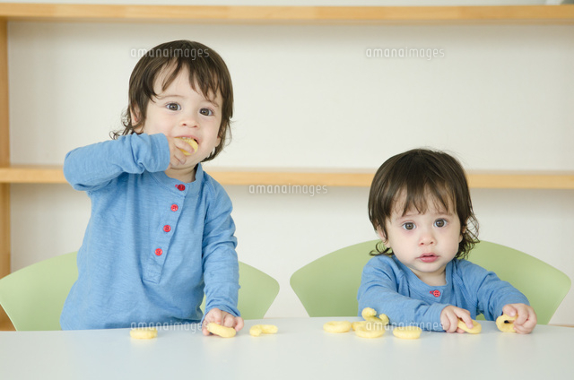 おやつを食べている双子の男の子たち の写真素材 イラスト素材 アマナイメージズ