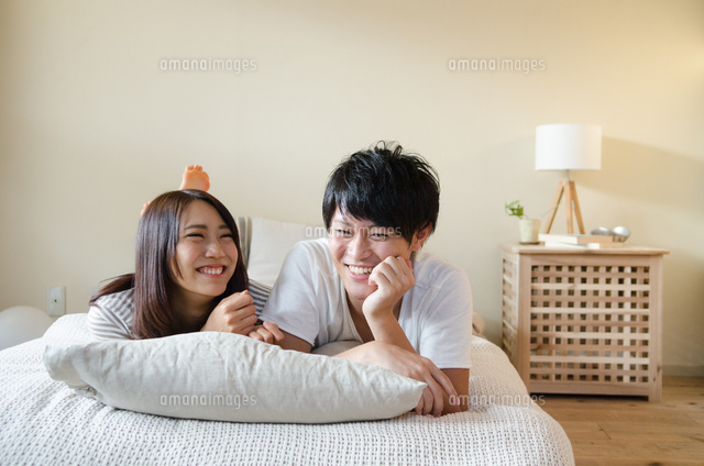 ベッドの上で笑うカップル の写真素材 イラスト素材 アマナイメージズ