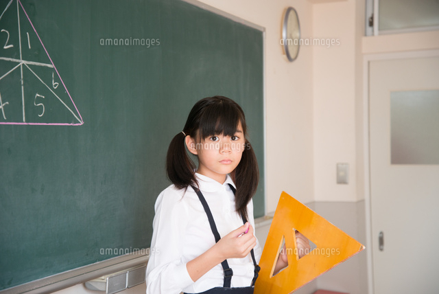 黒板の前で三角定規を持っている小学生の女の子 の写真素材 イラスト素材 アマナイメージズ