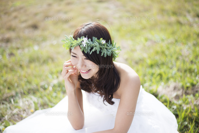草の上に座るウェディングドレス姿の女性 の写真素材 イラスト素材 アマナイメージズ